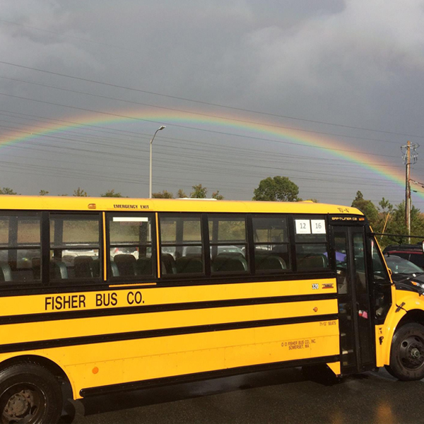 Fisher Bus Inc school bus with a rainbow in the background
