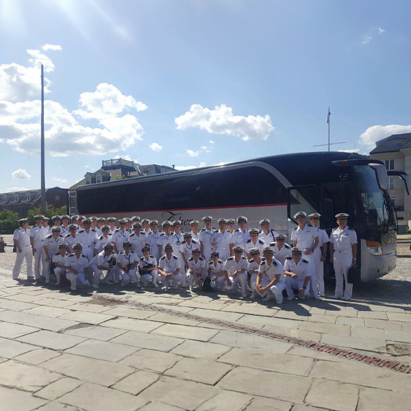 Members of the Navy in front of a Fisher Bus